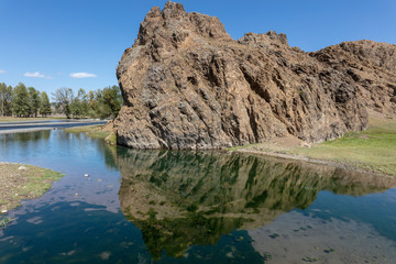 Fototapeta na wymiar rock reflected in a small lake in central Mongolia. reflection of the stone. The beautiful landscape of Mongolia. Sunny day in autumn, blue clear sky. Mirroring of the sky in the crystal clear water