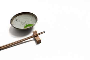 Wooden pairs of chopsticks and ceramic bowl on white background. traditional bowl isolated.
