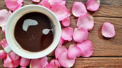 Pink petals rose and black coffee on the wood table for decoration on weeding and Valentine's day festival.