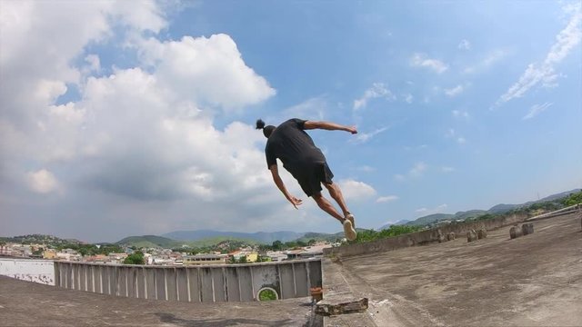 young freerunner performing a sideflip on a rooftop