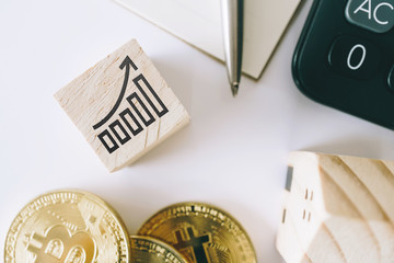 Graph rising up growht exponencial sign on wooden cube with objects such as gold coin, calculator and mini home model behide white clean background. Business financial loan property.