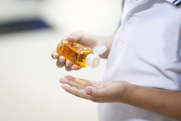 Close up, hand of schoolboy that applying alcohol gel as hand sanitizer at a school. - Powered by Adobe