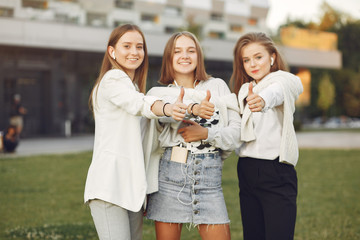 Students in a park. Girls on a campus. Friends with a phone.