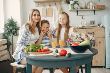 F in a kitchen. Blonde in a white t-shirt. Woman with vegetables