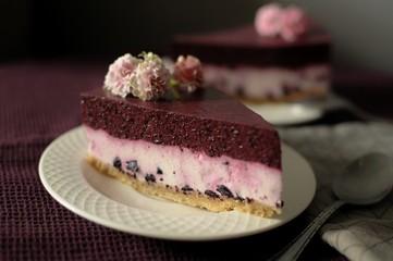 Piece of blueberry cheesecake on white plate on dark background.