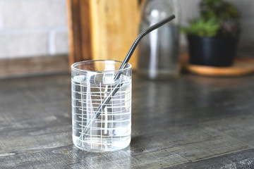 Glass of water with metallic straws on kitchen table. Eco natural, sustainable lifestyle, zero waste, plastic free concept.