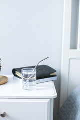 Eco natural metallic straw in glass with water on bedside table. sustainable lifestyle, zero waste, plastic free concept