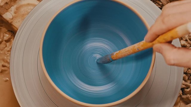 Painting a baked spinning pot in blue using with a brush