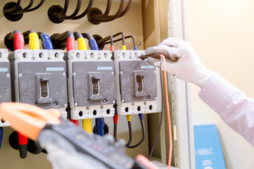 Technician is measuring voltage or current by voltmeter in control panel of power plan with...