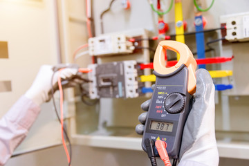 Technician is measuring voltage or current by voltmeter in control panel of power plan with...