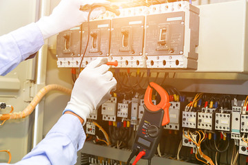 electrician measurements with multimeter tester in control panel.
