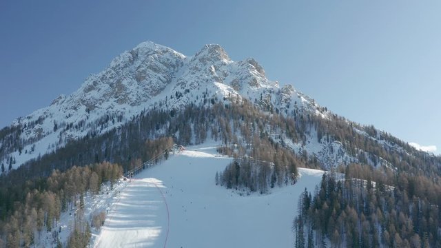 The skiing season in Plan de Corones Ski Resort, Italy. Skiers riding on the slopes. Beautiful weather, clear skies, and bright sun. Piz da Perez and Pre da Perez peaks towering in the back.