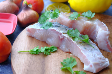 close up of raw fish on table with vegetables 