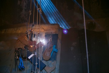 Abseiler wearing safety harness helmet leather jacket glove conducting wall structure repair with...