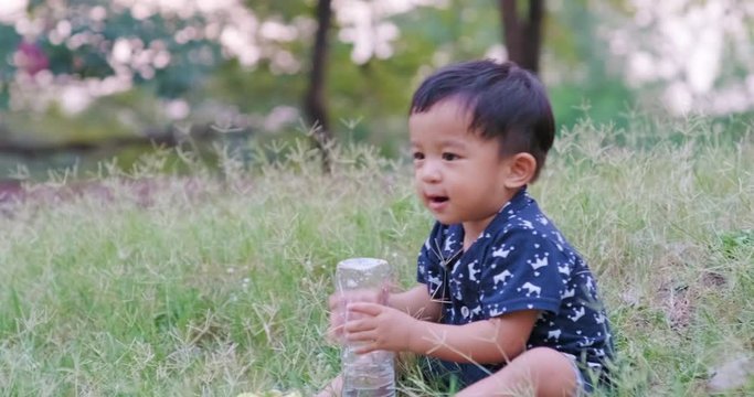 Cute asian baby boy playing in summer city park on green grass outdoor recreation