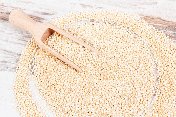Quinoa seeds with wooden scoop as source healthy vitamins on rustic board