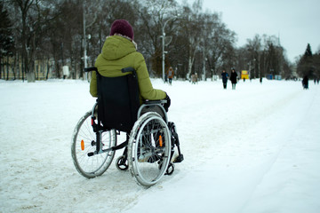 A disabled person in a wheelchair moves around the city in winter.