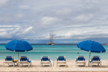 Blue beach chairs and umbrellas, ocean view, boats