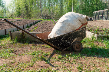 Handcart with a bag of fertilizers on the farm. Beginning of spring work on the land plot.