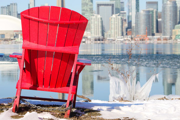 Muskoka chair / Adirondack chair on frozen lake with city skyline