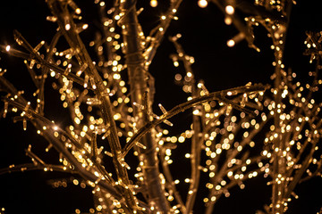 A tree decorated with garlands. Christmas light bulbs on twigs. LED lights shine with a warm yellow...