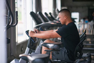Plakat sport man using exercise bike at the gym