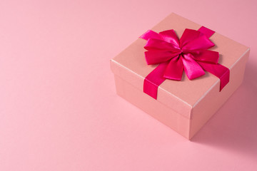 Valentine's Day celebration concept. A nice gift from a loved one. Box with a bow on a delicate pink background. Copy space. Flat lay. Close-up.