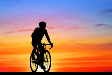 Naklejka na ściany i meble Silhouette Cycling on blurry sunrise sky background.
