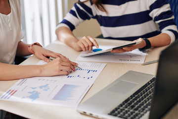 Businesswomen analyzing financial charts and discussing reports at meeting in office