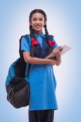Portrait of school girl in uniform holding book and bag