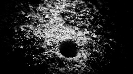 abstract grunge ant hole macro on the ground. use as a background or wallpaper, Black and white, so contrast and grainy.