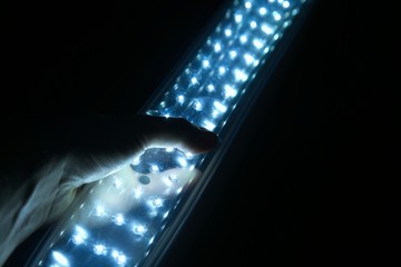 Hand holding a rechargeable LED light lantern in the dark. Load shedding in South Africa concept...