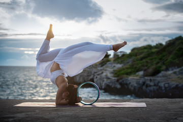 Young woman exercise yoga in nature sea sunset view. Modified Yoga Poses with Yoga Wheel,...