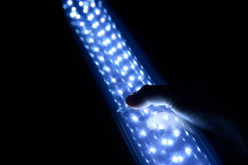 Hand holding a rechargeable LED light lantern in the dark. Load shedding in South Africa concept...