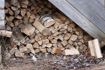 the woodpile of birch fire wood against the background of an old wooden house