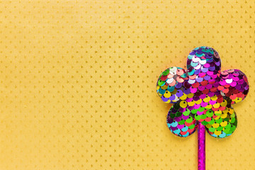 flower made of sequins on sparkling golden background. Minimal flat lay, copy space