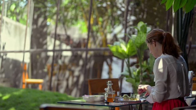 woman eating avocado toast breakfast in outdoor street cafe. woman in resort vacation on palm tree background. young female drink tea at lunch. concept outside, summer, tropic
