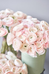Lot of flowers Persian buttercup. Bunch pale pink ranunculus flowers on light gray background. Glass vase on vintage wooden table. Wallpaper
