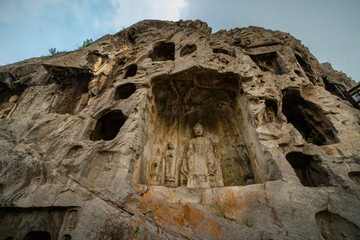 Buddha in a small cave on west hill limestone cliff. Longmen Grottoes Luoyang, Henan province, China