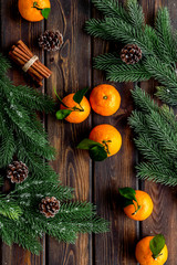 Tangerines near fir branches. New Year composition on dark wooden background top-down