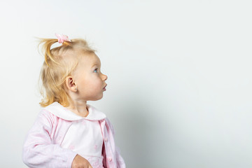 Little child looks away on a light background. Girl in dress