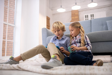 Boy and girl sitting on the floor with gadgets