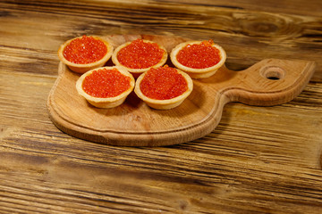 Tartlets with red caviar on a wooden table