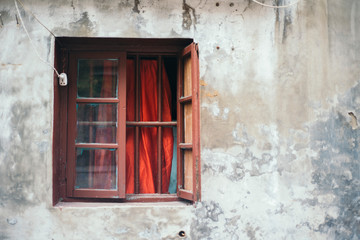 Obraz na płótnie Canvas Open window with red frame on shabby wall of countryside house in China