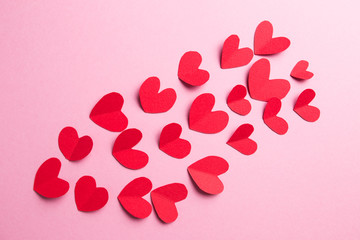 A lot of small hearts of red color against on a pink background. Happy Valentine's Day.