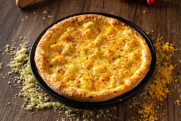 whole italian pizza on wood table with ingredients