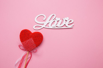 Lettering from wooden letters love on a pink isolated background. Heart in the form of candy on a stick.