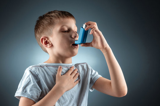 Portrait of a boy using an asthma inhaler to treat inflammatory diseases, shortness of breath. The concept of treatment for cough, allergies, respiratory tract disease. - Powered by Adobe