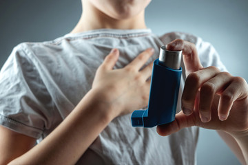 The boy holds an asthma inhaler in his hands to treat inflammatory diseases, shortness of breath....