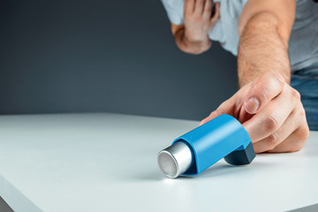 The male hand reaches for an asthma inhaler, an asthmatic attack. The concept of treatment of...